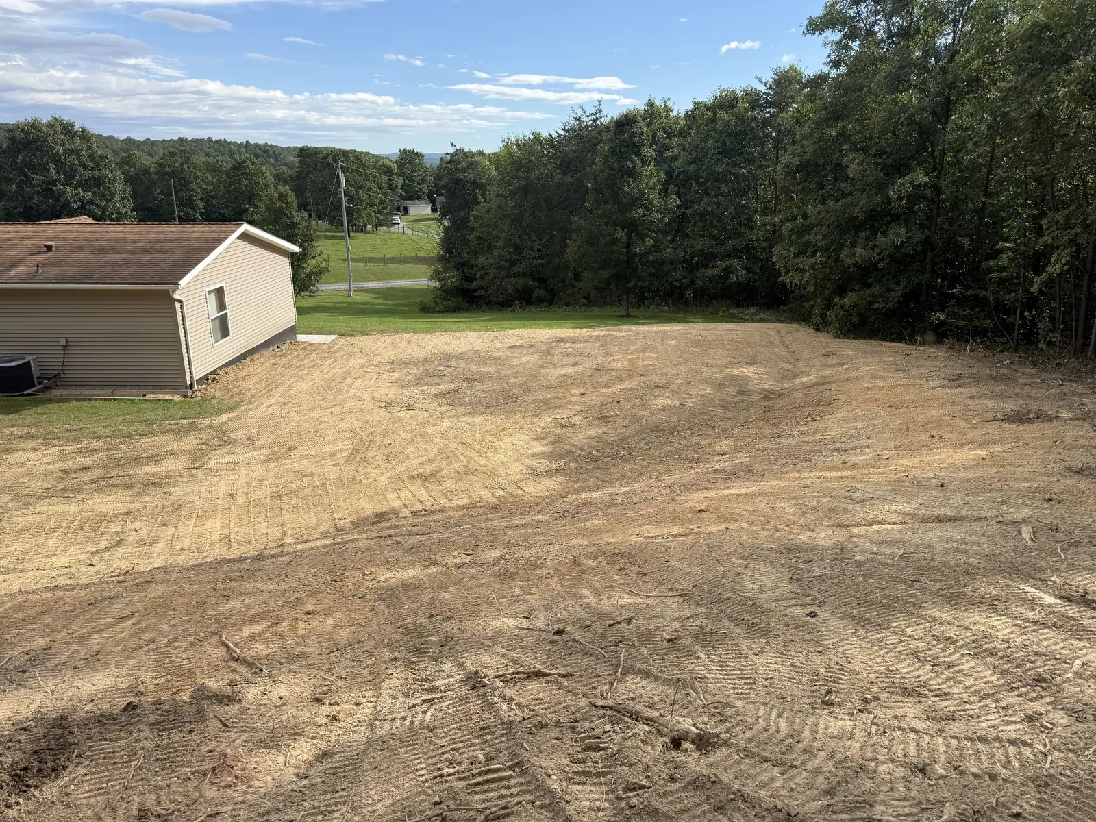 Graded yard seen from the top of the bank, track marks across the fresh grade