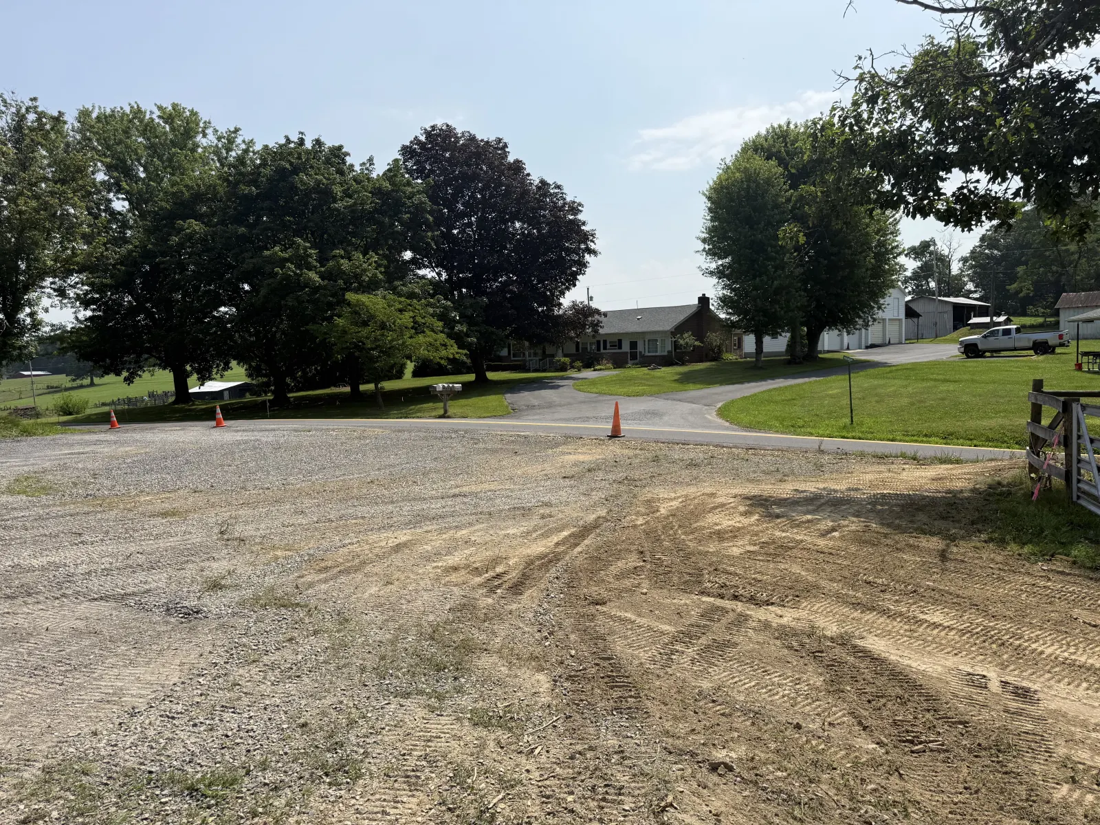 Graded gravel pad beside a paved road with the spoil smoothed out