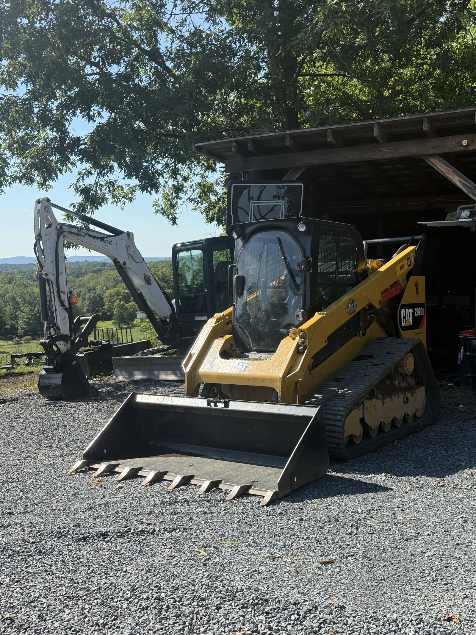Compact track loader and mini excavator parked side by side at the shop