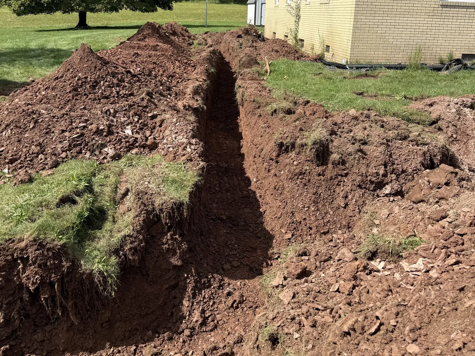 Trench dug across a yard with the spoil piled alongside